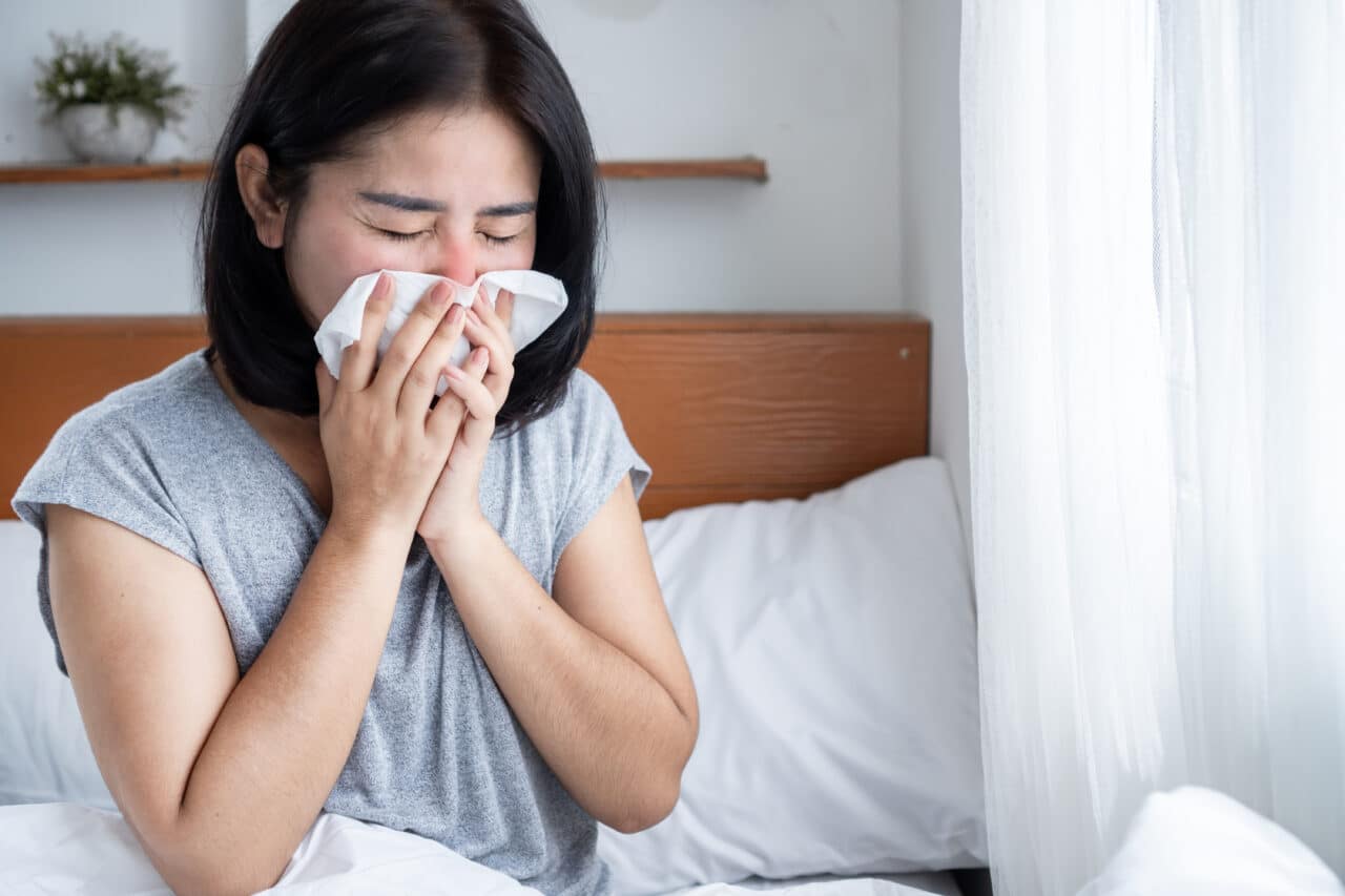 Woman in bed, suffering from sinus symptoms due to dust mite allergy