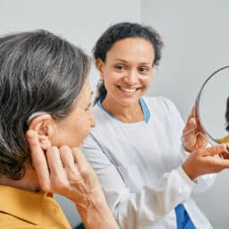 Woman tries on her new hearing aid at her first hearing aid fitting appointment.