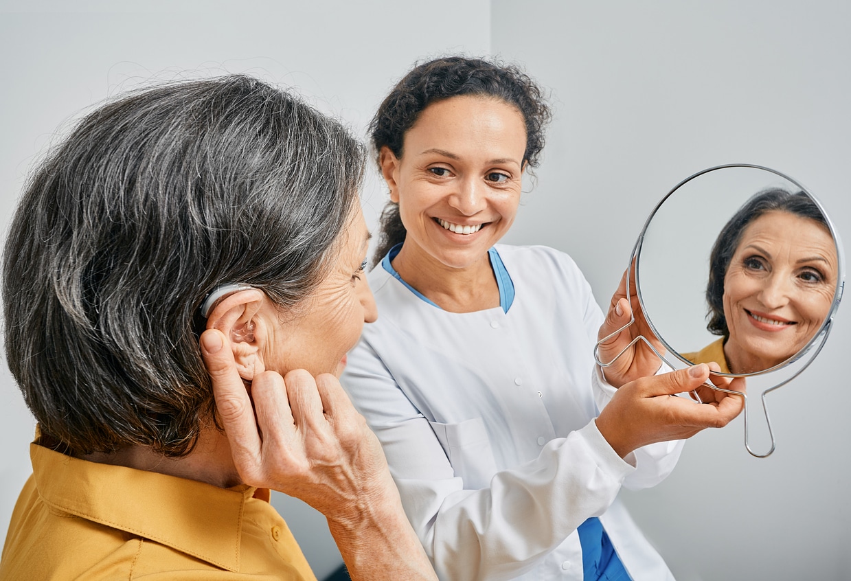 Woman tries on her new hearing aid at her first hearing aid fitting appointment.