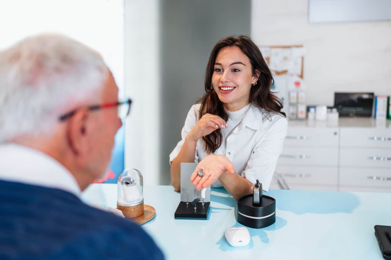Helpful audiologist advises a patient at their first hearing aid fitting.